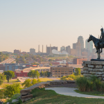 Kansas city skyline with a statue of a man riding a horse in front of it